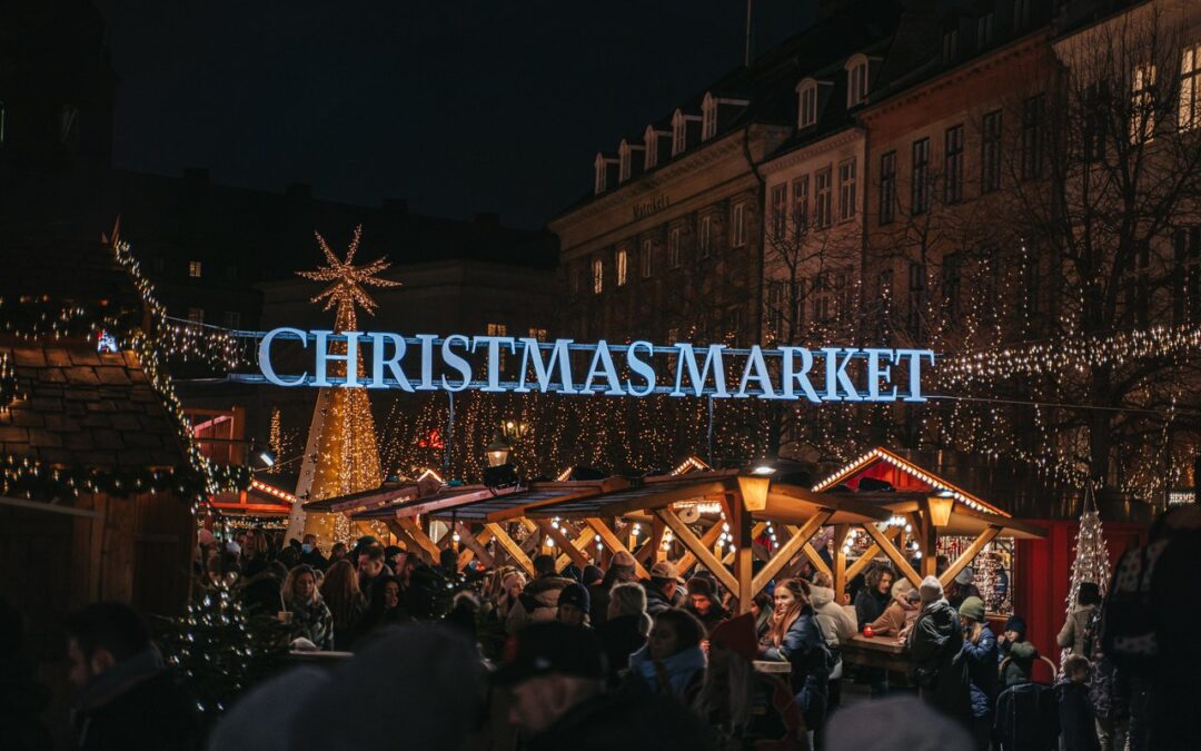 Crowd enjoying Copenhagen Christmas market at night with festive lights and cozy wooden stalls