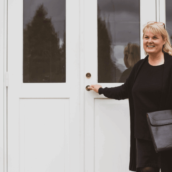 Rikke V. Stoltz foran hvid dør med briefcase – klar til strategisk fundraising-sparring